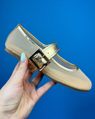 A pair of metallic gold Mary Jane shoes with gold-tone straps and buckles, displayed on a solid blue background.