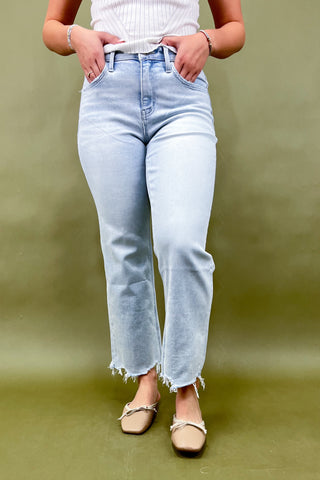 Person wearing light blue jeans and a white top on a green background