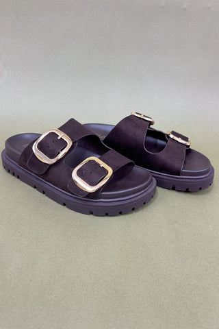 brown sandals with gold buckles on a light green background