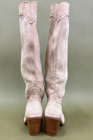 Pair of light pink suede knee-high boots on a green background
