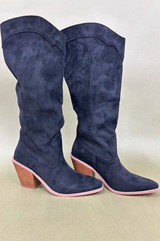 Pair of blue knee-high boots with pink soles on a beige background