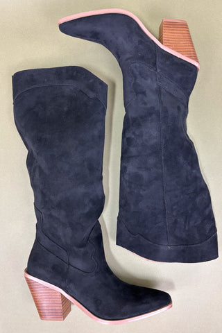 Navy blue suede boots with pink block heels on a beige background