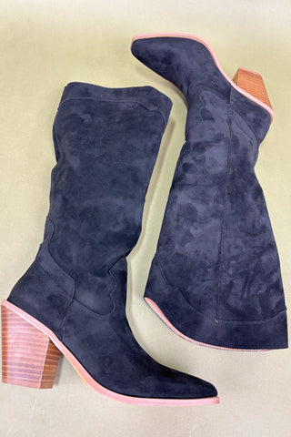 Navy blue suede boots with pink accents on a beige background