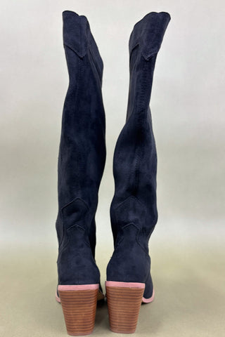 Navy blue knee-high boots with brown soles on a light beige background