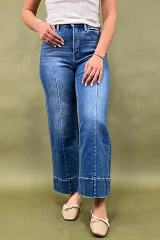 Person wearing blue jeans on a plain background