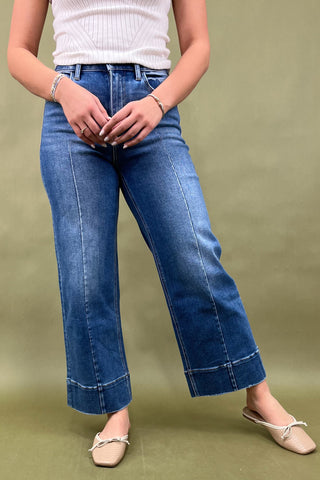 Person wearing blue jeans and a white top on a green background