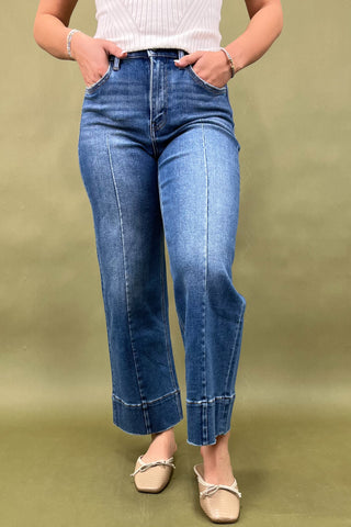 Person wearing blue jeans on a plain background