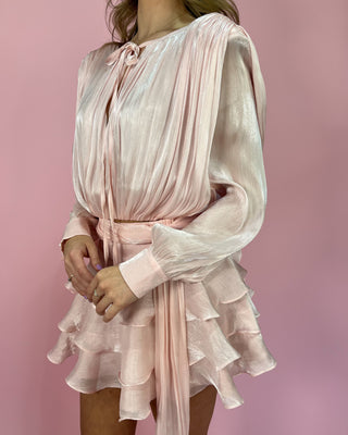 Light pink dress with ruffled layers on a pink background
