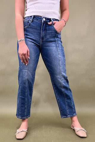 Person wearing blue jeans and a white top on a plain background
