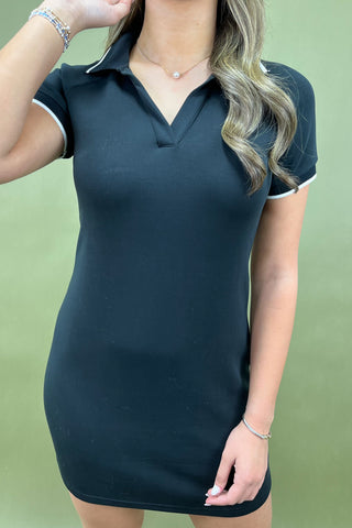 Woman wearing a dark blue dress with white trim against a green background