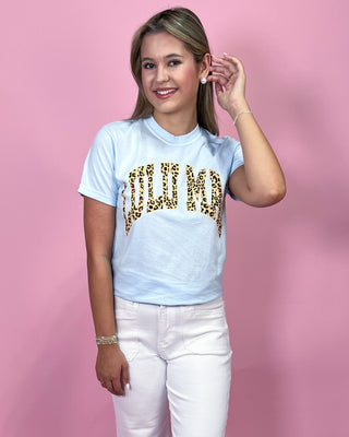 Woman wearing a light blue t-shirt with leopard print text on a pink background