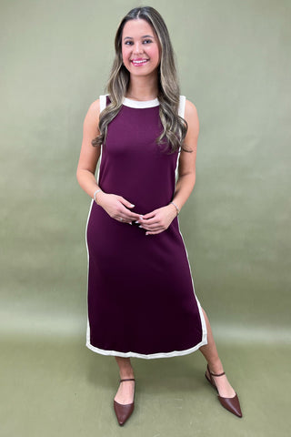 Woman wearing a purple dress with white trim against a green background