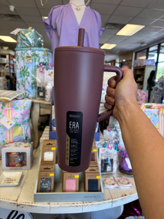 Person holding a purple mug with a straw in a store setting