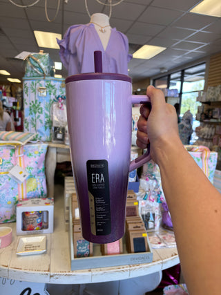 Purple insulated mug with handle held by a hand in a store setting