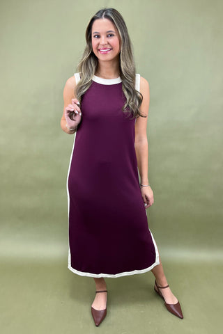 Woman wearing a purple dress with white trim on a green background