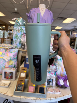 Person holding a light blue mug with 'ERA' branding in a store setting