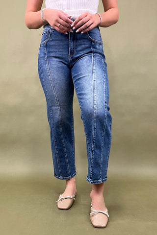 Person wearing blue jeans and a white top on a green background