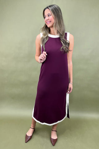 Woman wearing a purple dress with white trim against a green background