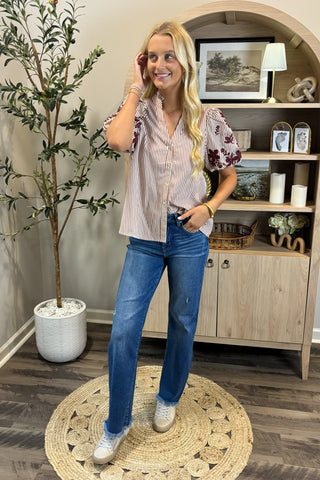 Woman standing in a room with a plant and wooden cabinet.