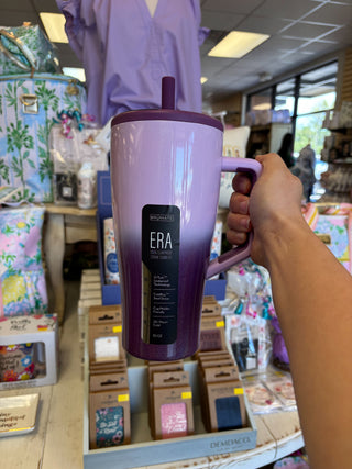 Person holding a purple mug with 'ERA' branding in a store setting
