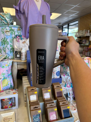 Person holding a gray mug with 'ERA' branding in a store setting