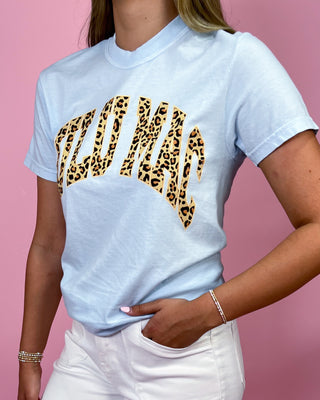 Light blue t-shirt with leopard print text worn by a person on a pink background