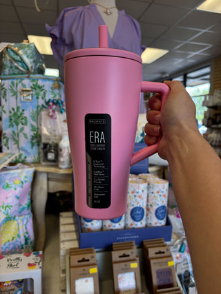 Pink mug with a handle held by a person in a store setting