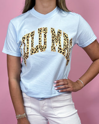 Person wearing a light blue t-shirt with leopard print text on a pink background