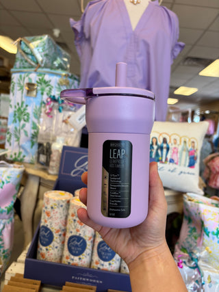 Hand holding a purple bottle labeled 'LEAP' in a store setting