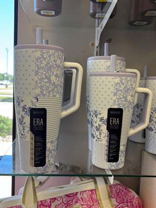 Floral-patterned tumblers with 'ERA' branding on a glass shelf.