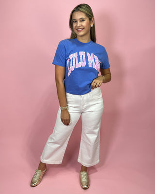 Woman wearing a blue t-shirt with 'PUMA' printed on it against a pink background