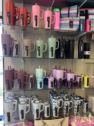 Display of colorful mugs and tumblers on shelves with visible brand labels.