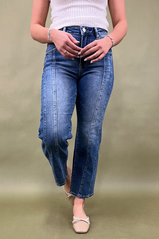 Person wearing blue jeans and a white top on a beige background