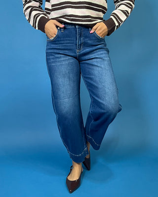 Dark wash high rise wide leg crop jeans with subtle fading and seamed cuff hem detail.