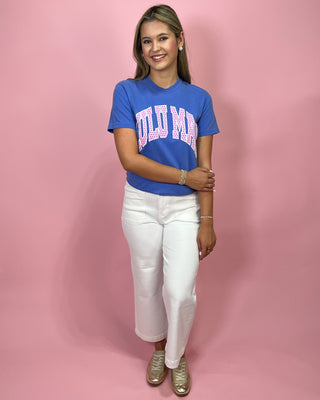 Person wearing a blue t-shirt with pink text and white pants on a pink background