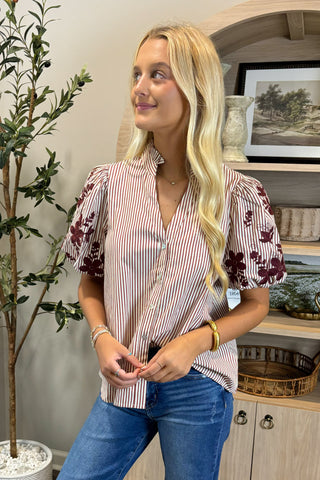 Woman wearing a striped shirt with floral sleeves in a home setting