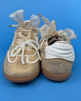 A pair of beige suede sneakers with white mesh panels, white laces decorated with pearl-like beads