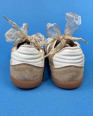 A pair of beige suede sneakers with white mesh panels, white laces decorated with pearl-like beads