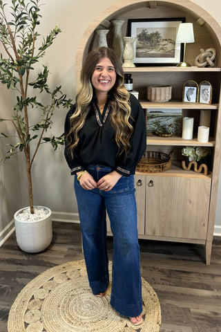 Woman standing in a room with wooden shelves and decorative items