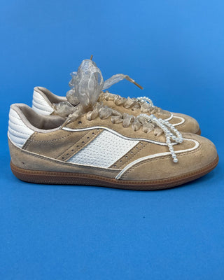 A pair of beige suede sneakers with white mesh panels, white laces decorated with pearl-like beads