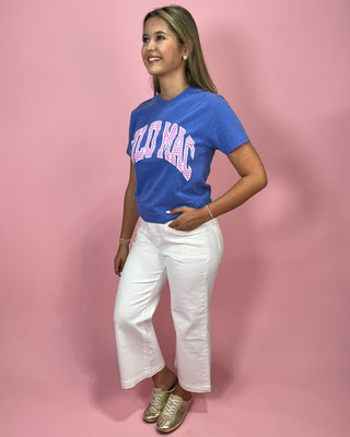 Woman wearing a blue t-shirt with pink text and white pants on a pink background