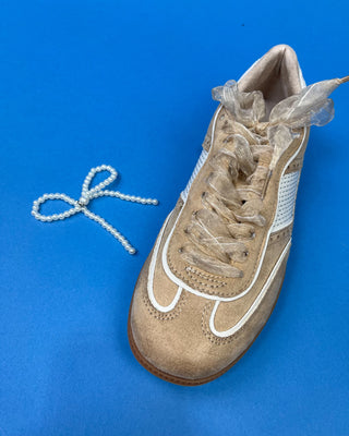 A pair of beige suede sneakers with white mesh panels, white laces decorated with pearl-like beads