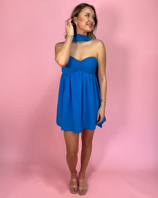 Woman wearing a blue dress against a pink background