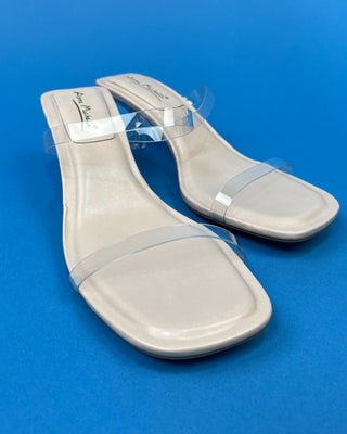 A pair of beige heeled slide sandals with clear transparent straps
