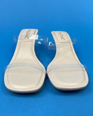 A pair of beige heeled slide sandals with clear transparent straps