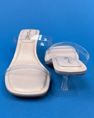 A pair of beige heeled slide sandals with clear transparent straps