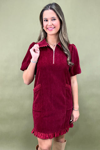 Woman wearing a burgundy dress with a green background