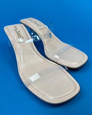 A pair of beige heeled slide sandals with clear transparent straps