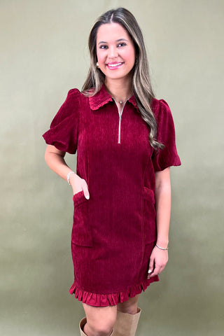 Woman wearing a burgundy dress with a plain background