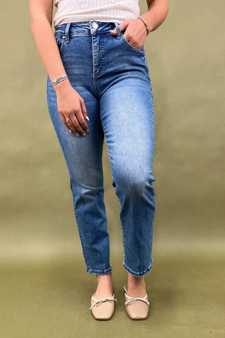 Person wearing blue jeans and white shoes on a green background